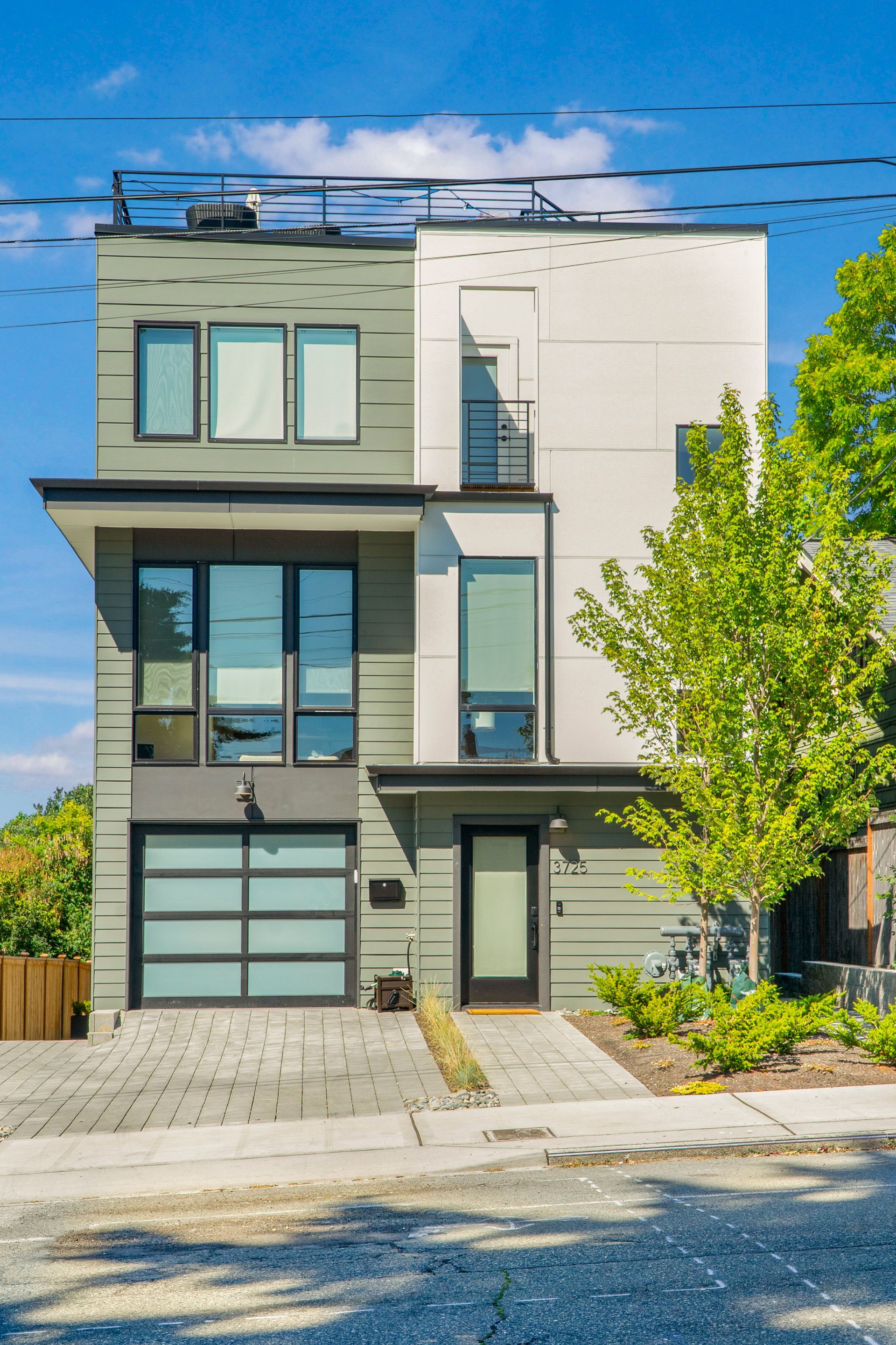 A modern house with a garage and a balcony on top of it.