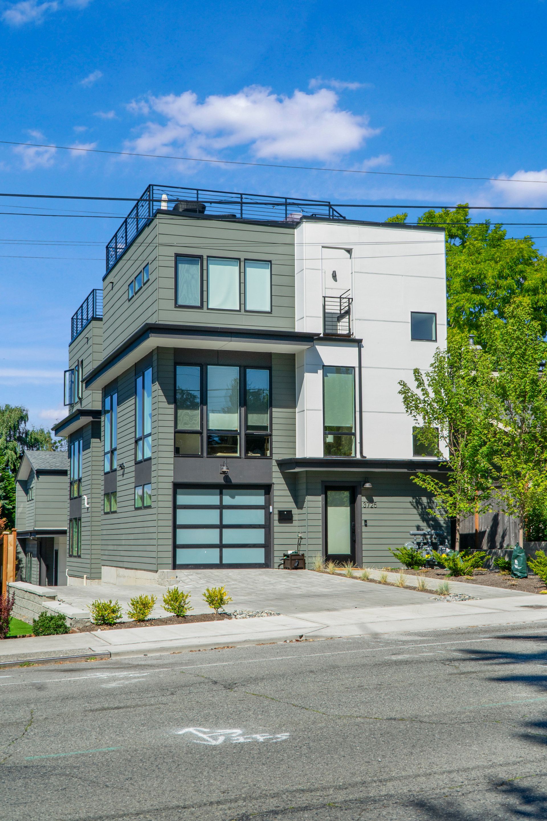 A modern apartment building with a garage and a rooftop deck.