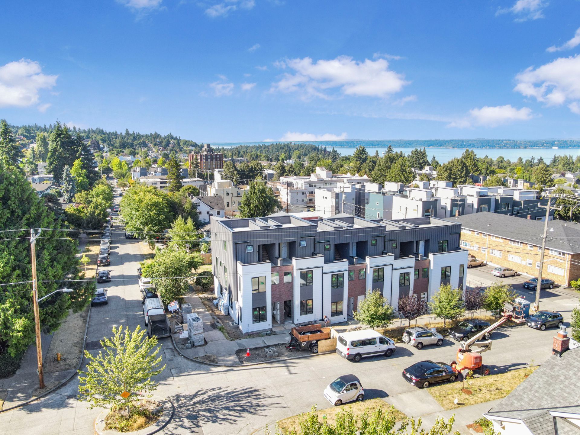 An aerial view of a building under construction in a city with cars parked in front of it.