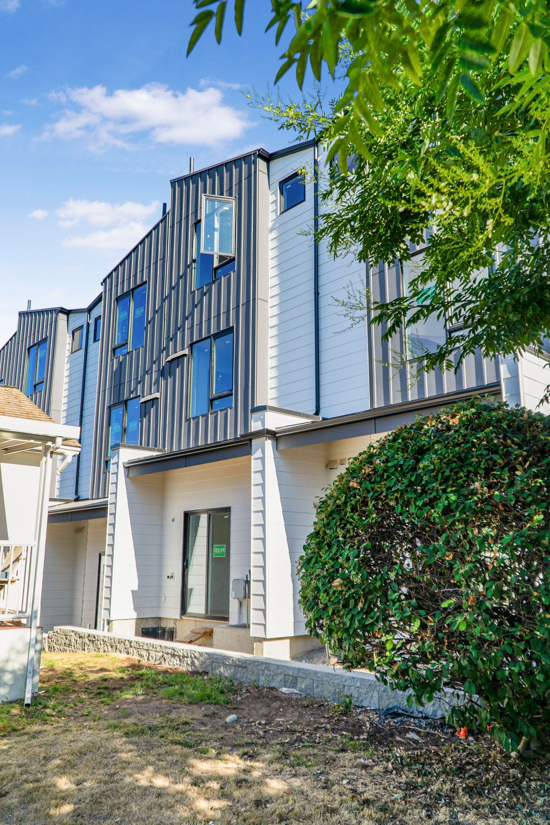 A large white building with a lot of windows and a bush in front of it.