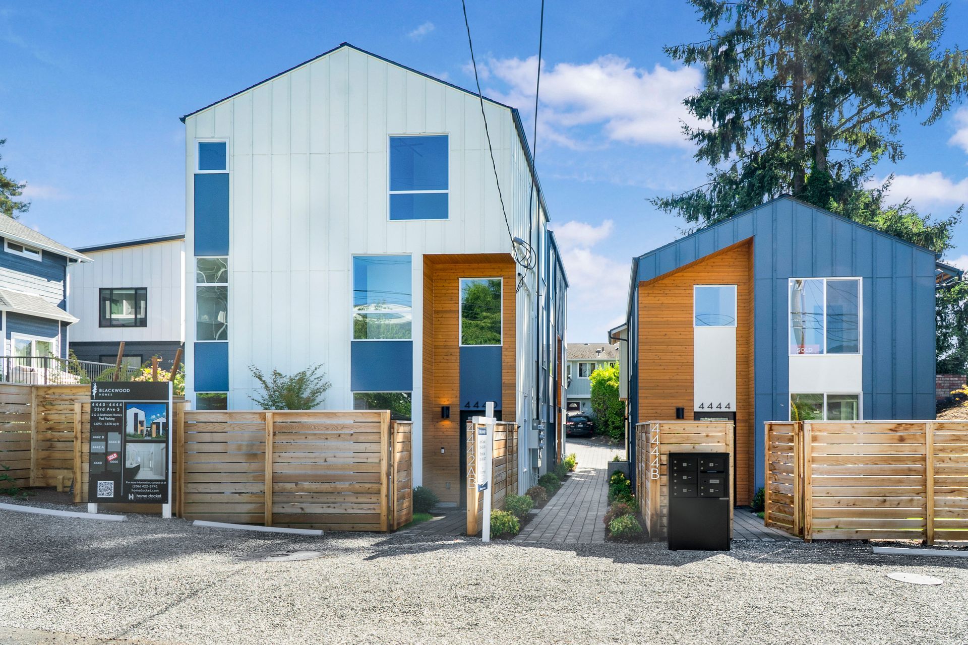 Two houses are sitting next to each other on a gravel road.