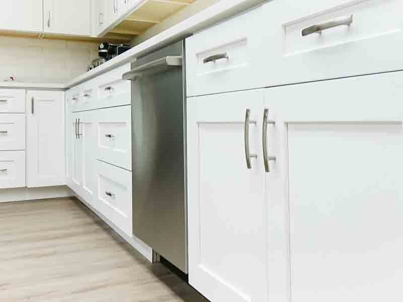 A kitchen with white cabinets and a stainless steel dishwasher.