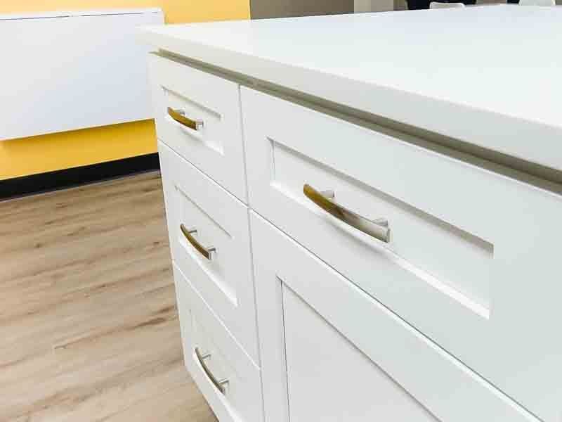 A close up of a white cabinet with gold handles in a kitchen.