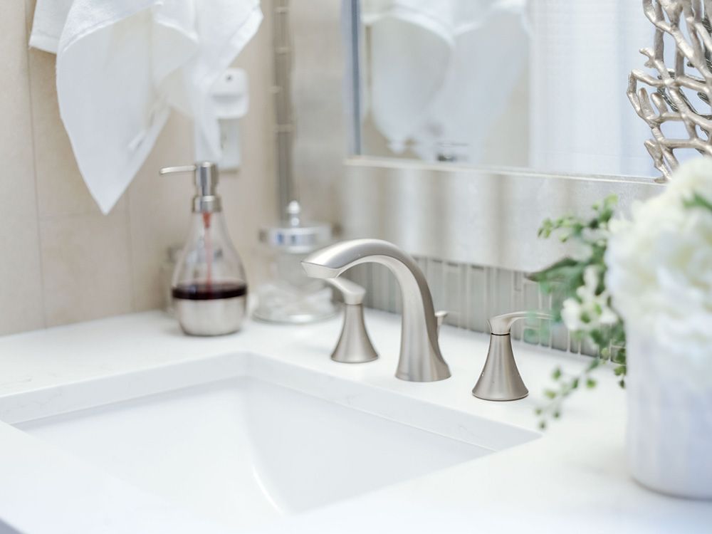 A bathroom sink with a soap dispenser and a vase of flowers