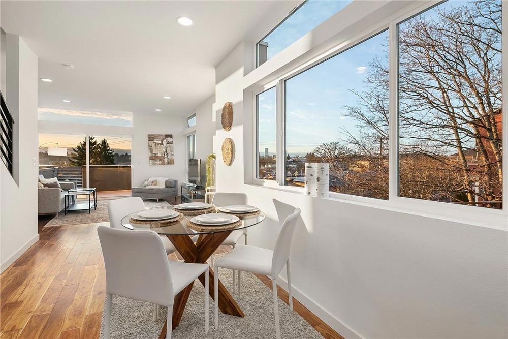 A dining room with a table and chairs and a large window.