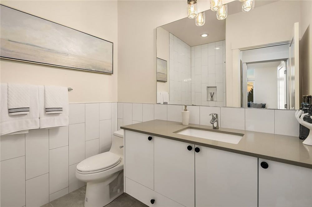 A bathroom with a toilet , sink and mirror.