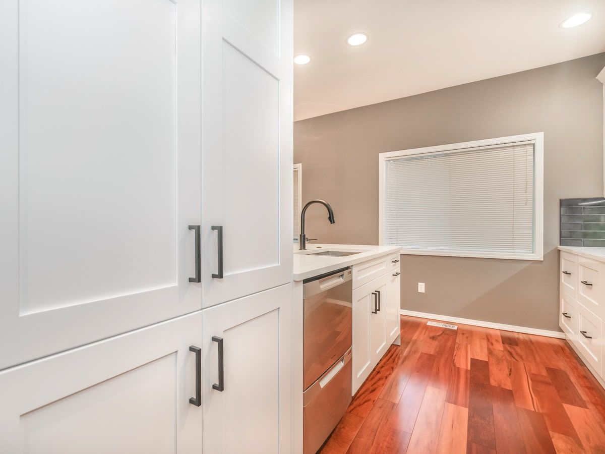 A kitchen with white cabinets and hardwood floors
