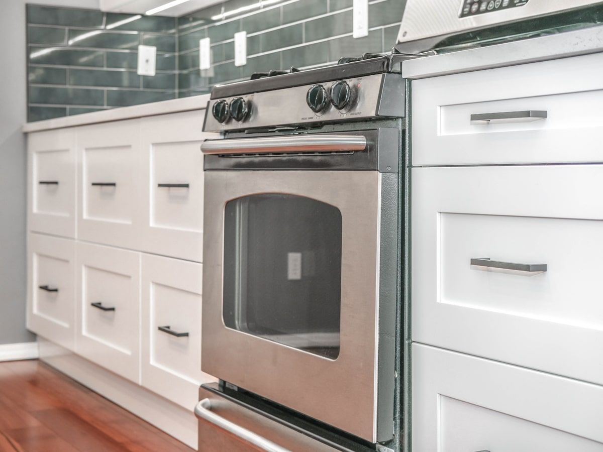 A kitchen with stainless steel appliances and white cabinets.