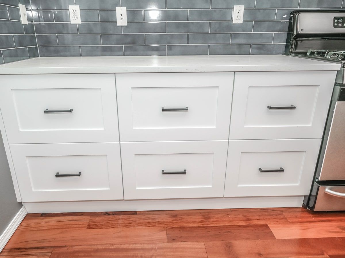 A kitchen with white cabinets and a wooden floor.