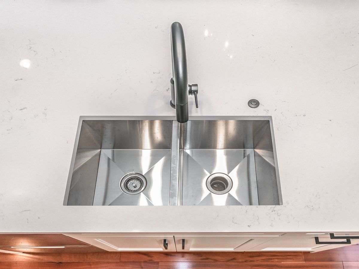 A stainless steel kitchen sink with a faucet on a white counter top.