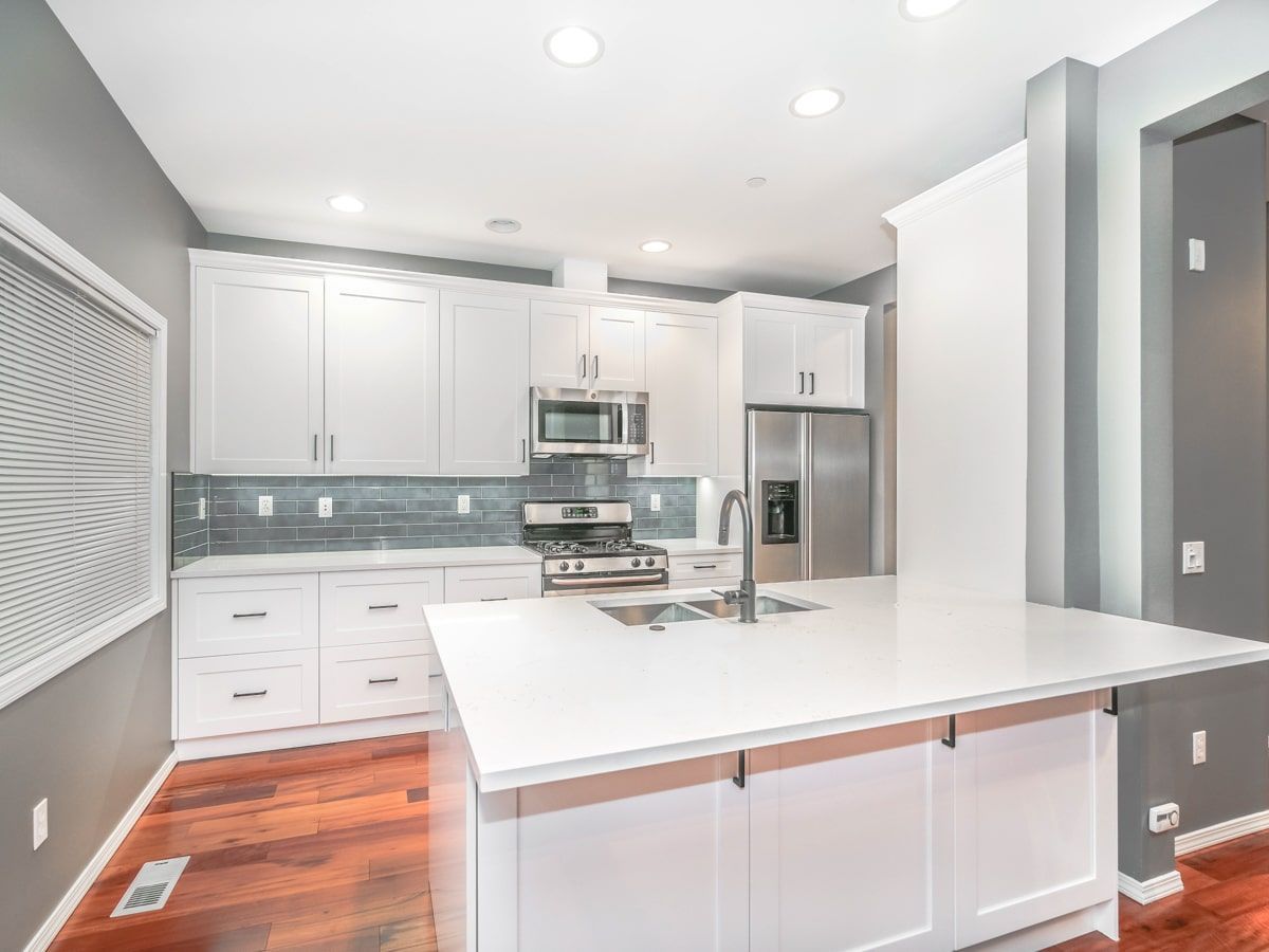 A kitchen with white cabinets , stainless steel appliances , and a large island.