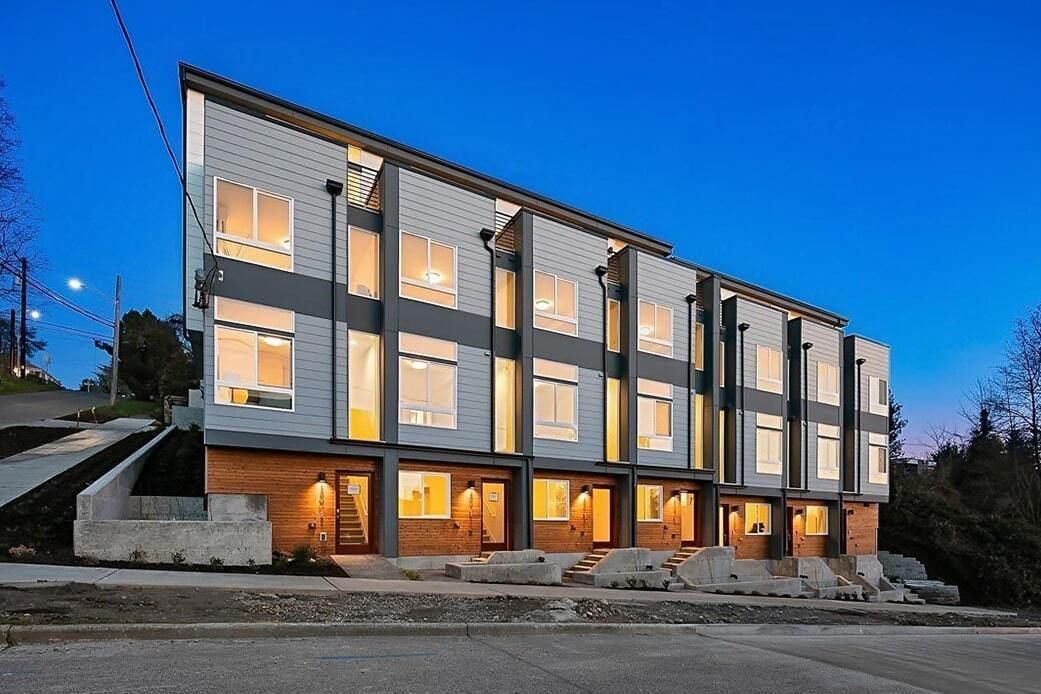 A row of apartment buildings are lined up next to each other on a hill.