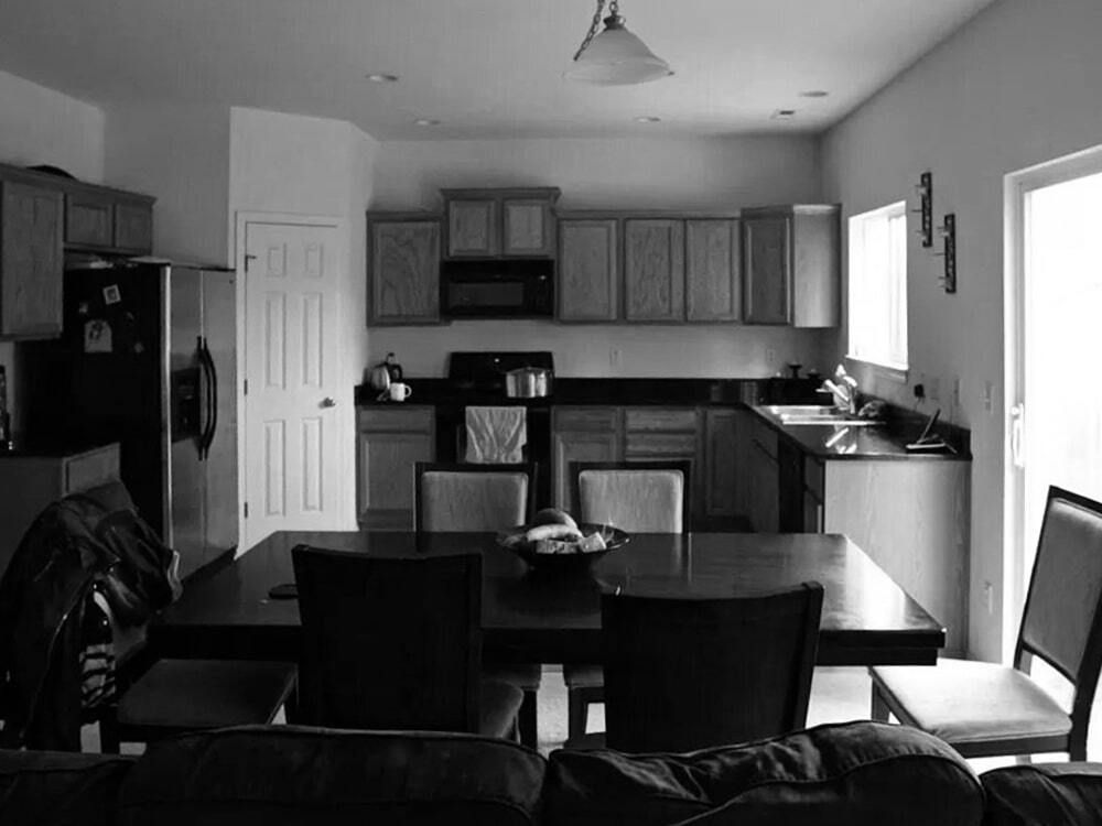 A black and white photo of a kitchen with a table and chairs
