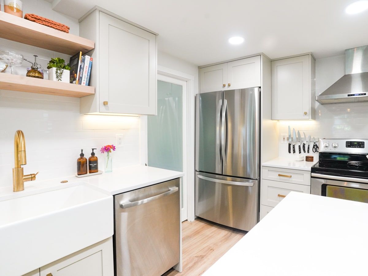 A kitchen with stainless steel appliances , white cabinets , a sink and a refrigerator.