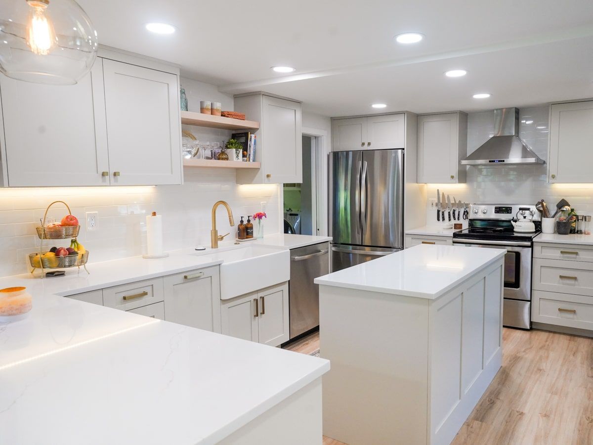 A kitchen with white cabinets , stainless steel appliances , and a large island.