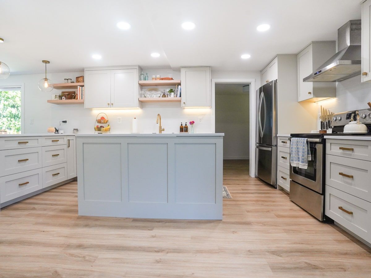 A kitchen with white cabinets , stainless steel appliances , and a large island.