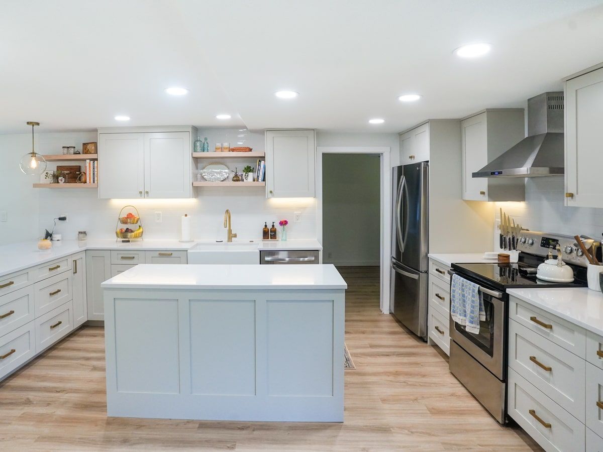 A kitchen with white cabinets , stainless steel appliances , and a large island.