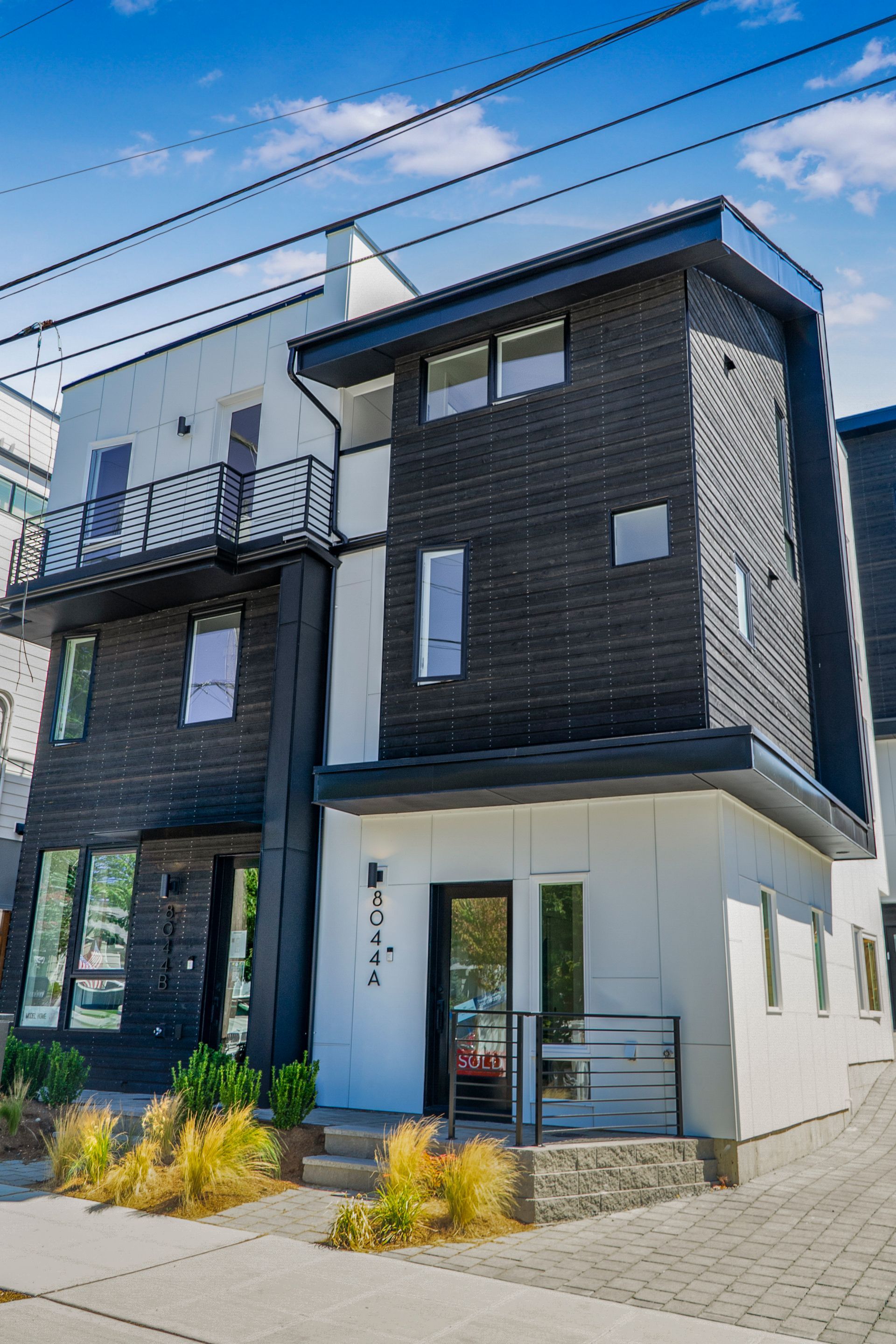 A black and white apartment building with a balcony and a fire escape.