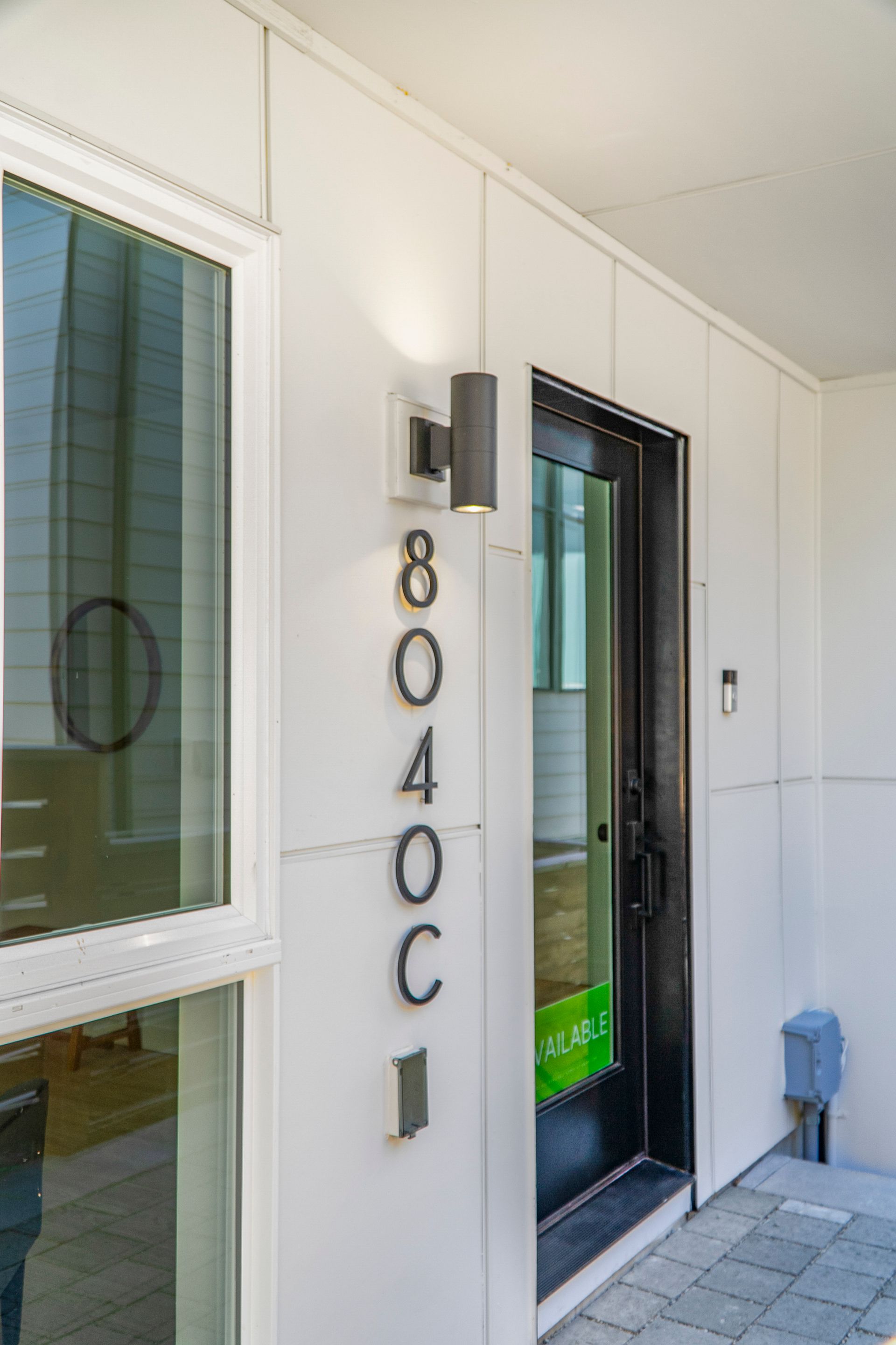 The front door of a house with a black door and a white wall.