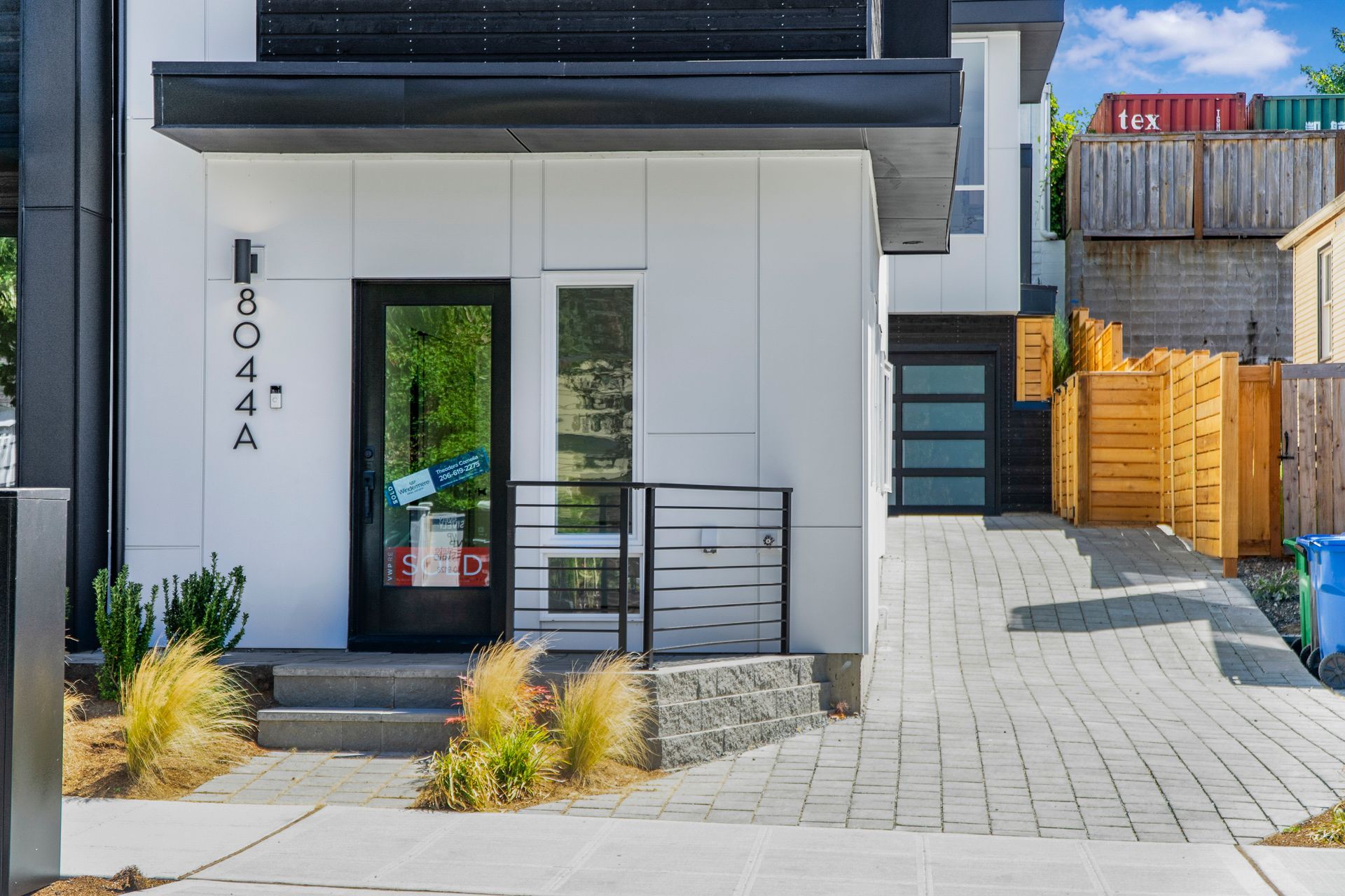 A white house with a black door and a brick driveway