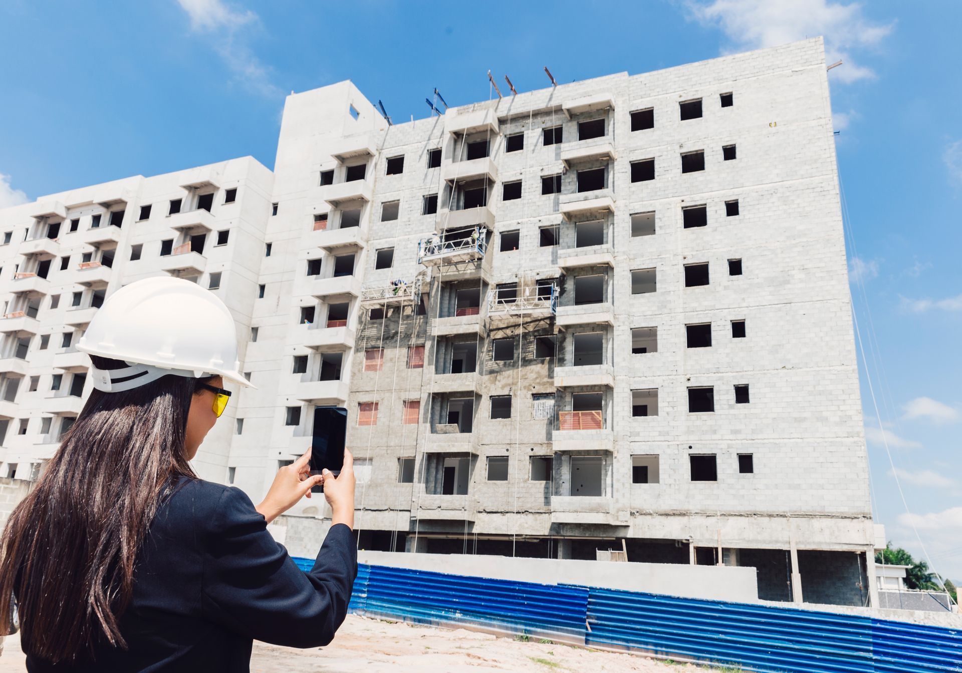 A woman is taking a picture of a building under construction.