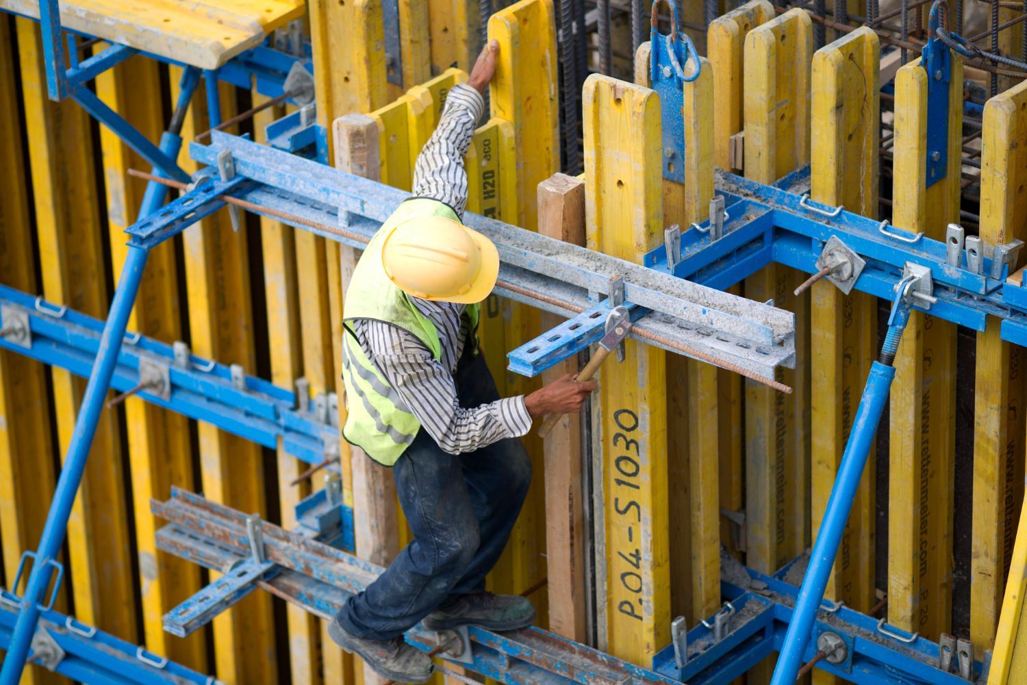 A construction worker is working on a wall at a construction site.