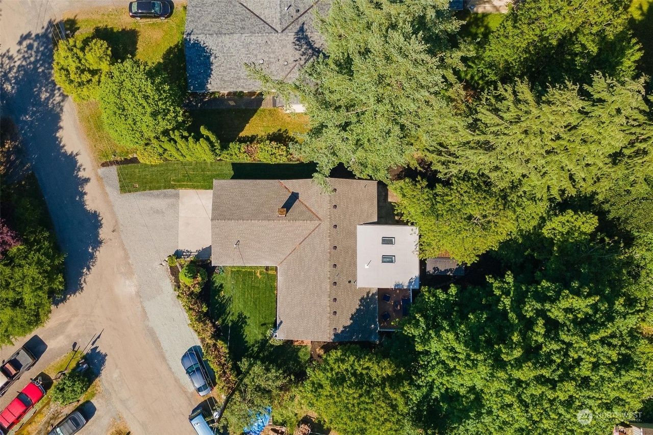 An aerial view of a house surrounded by trees and a parking lot.