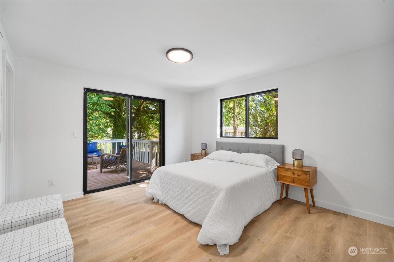 A bedroom with a large bed and sliding glass doors leading to a deck.