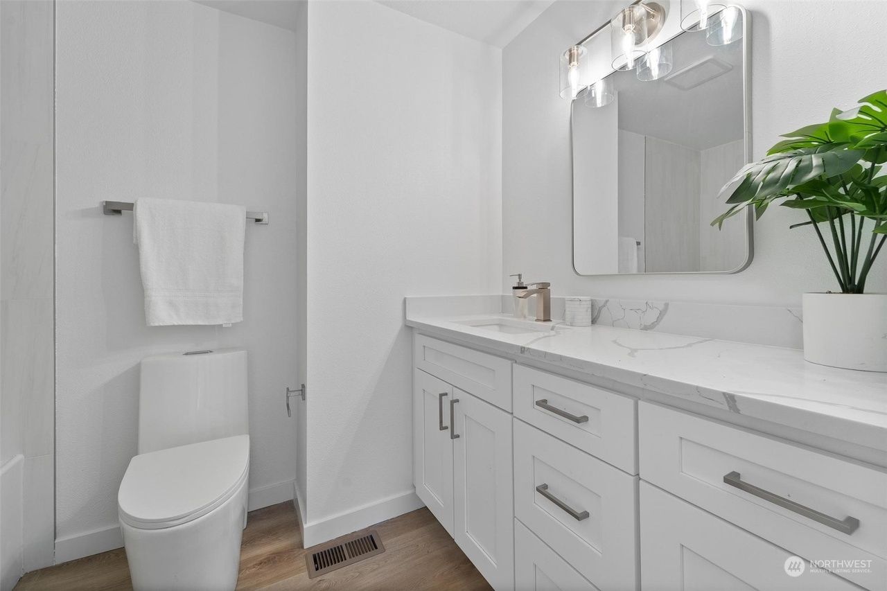 A bathroom with a toilet , sink and mirror.