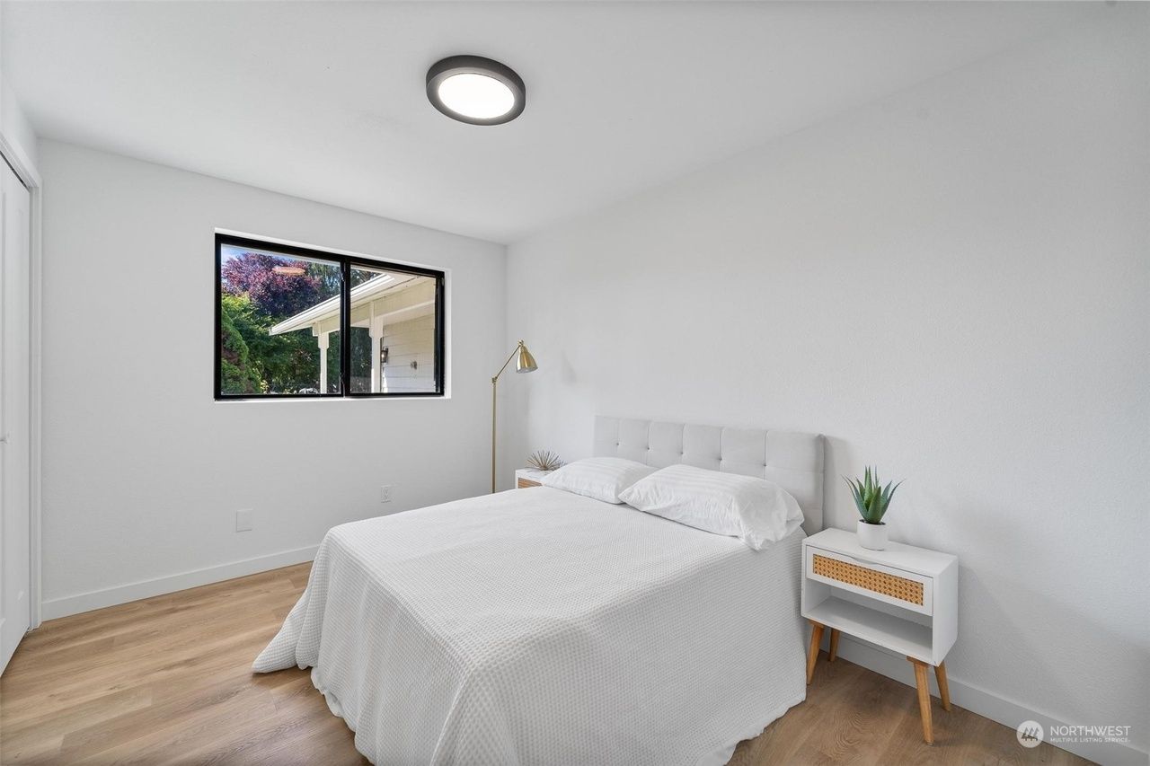 A bedroom with a bed , nightstand , and window.