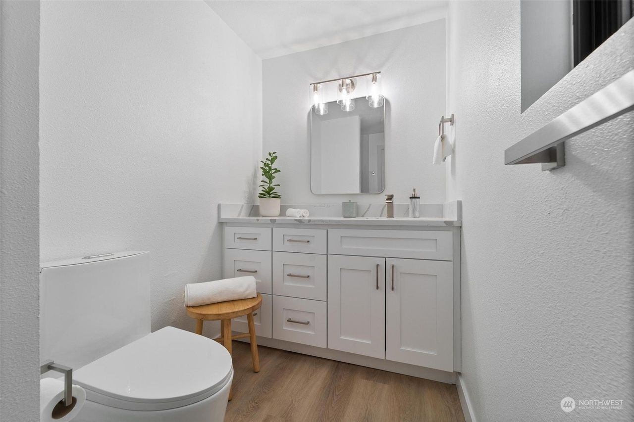 A bathroom with a toilet , sink and mirror.