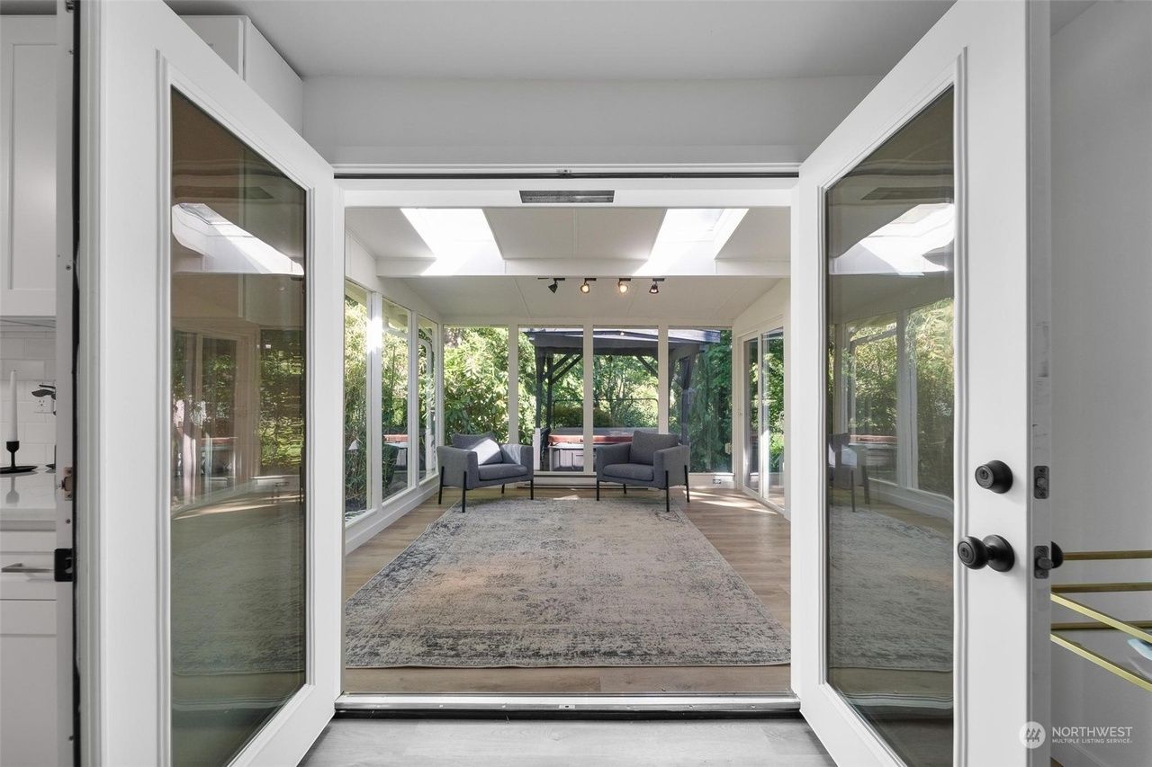 A living room with a lot of windows and a rug.