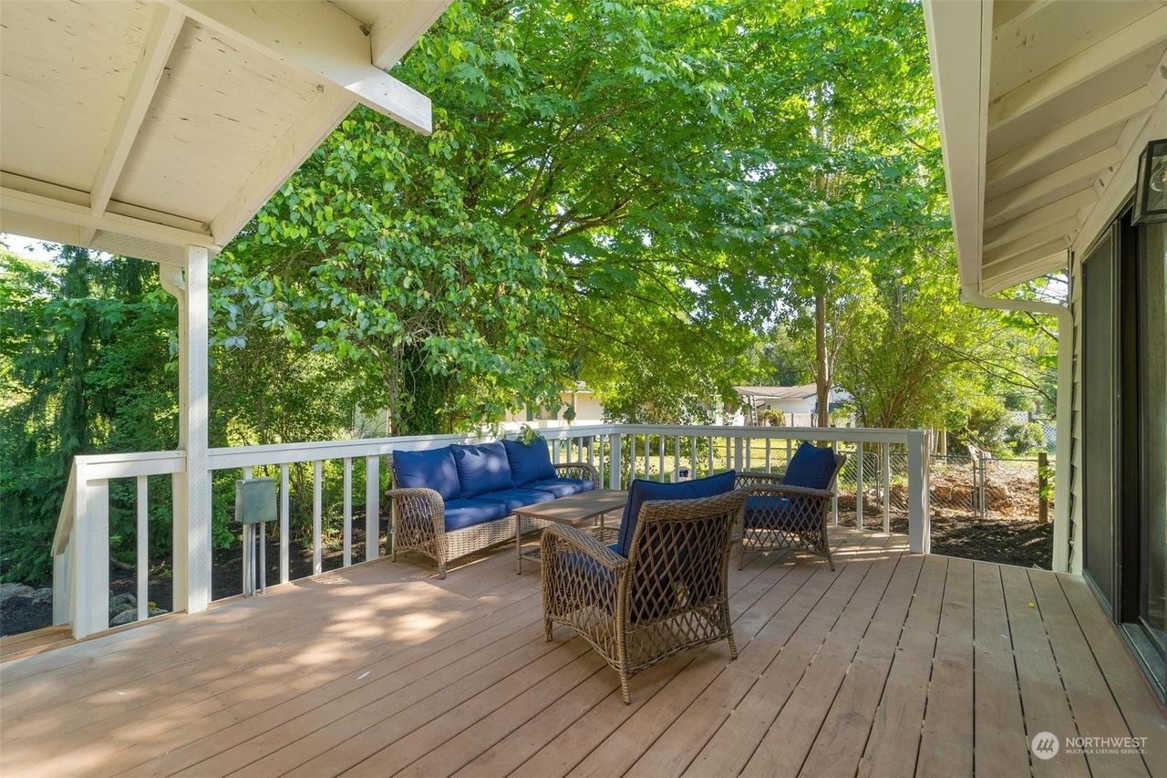 There is a large deck with a couch and chairs on it.