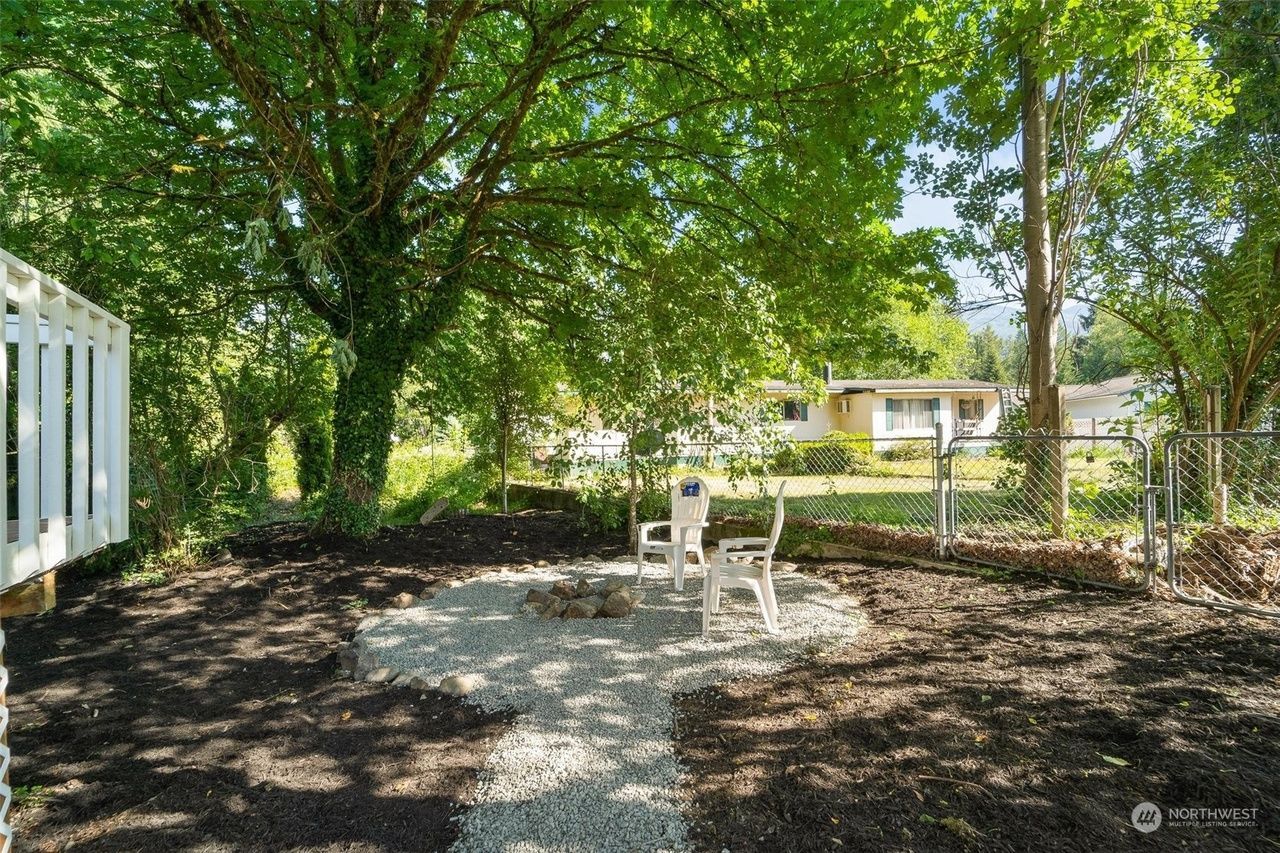 There is a fire pit in the middle of the backyard surrounded by trees.