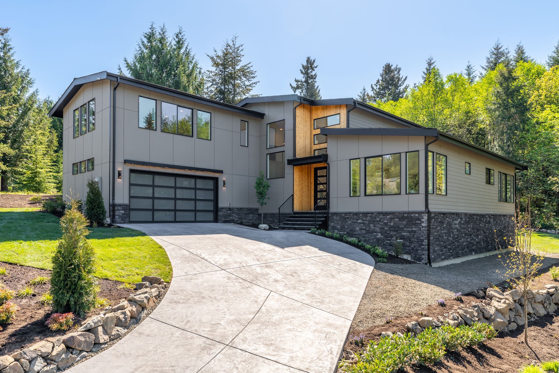 A large house with a driveway leading to it is surrounded by trees.