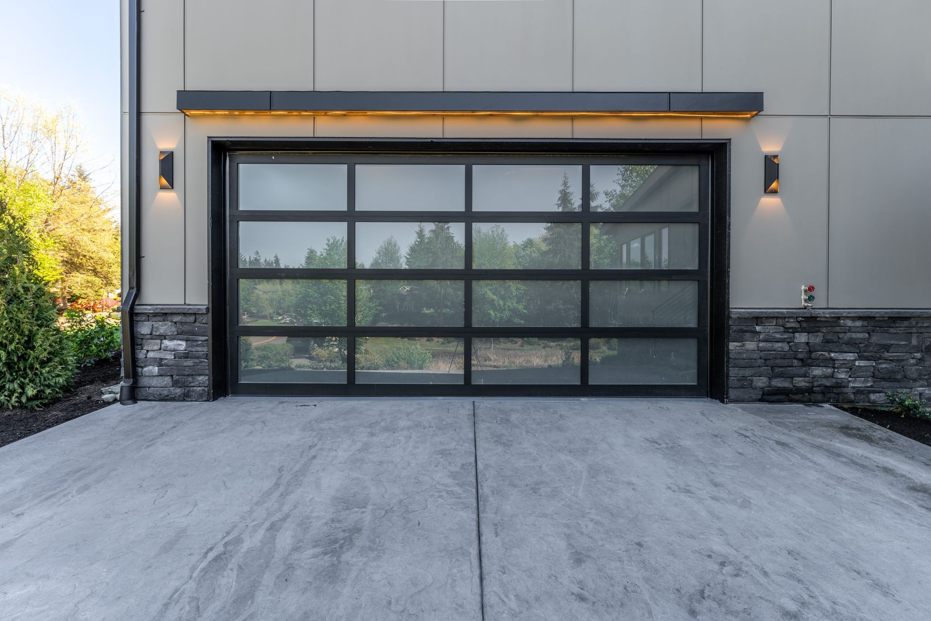 A modern garage door with a concrete driveway in front of it.