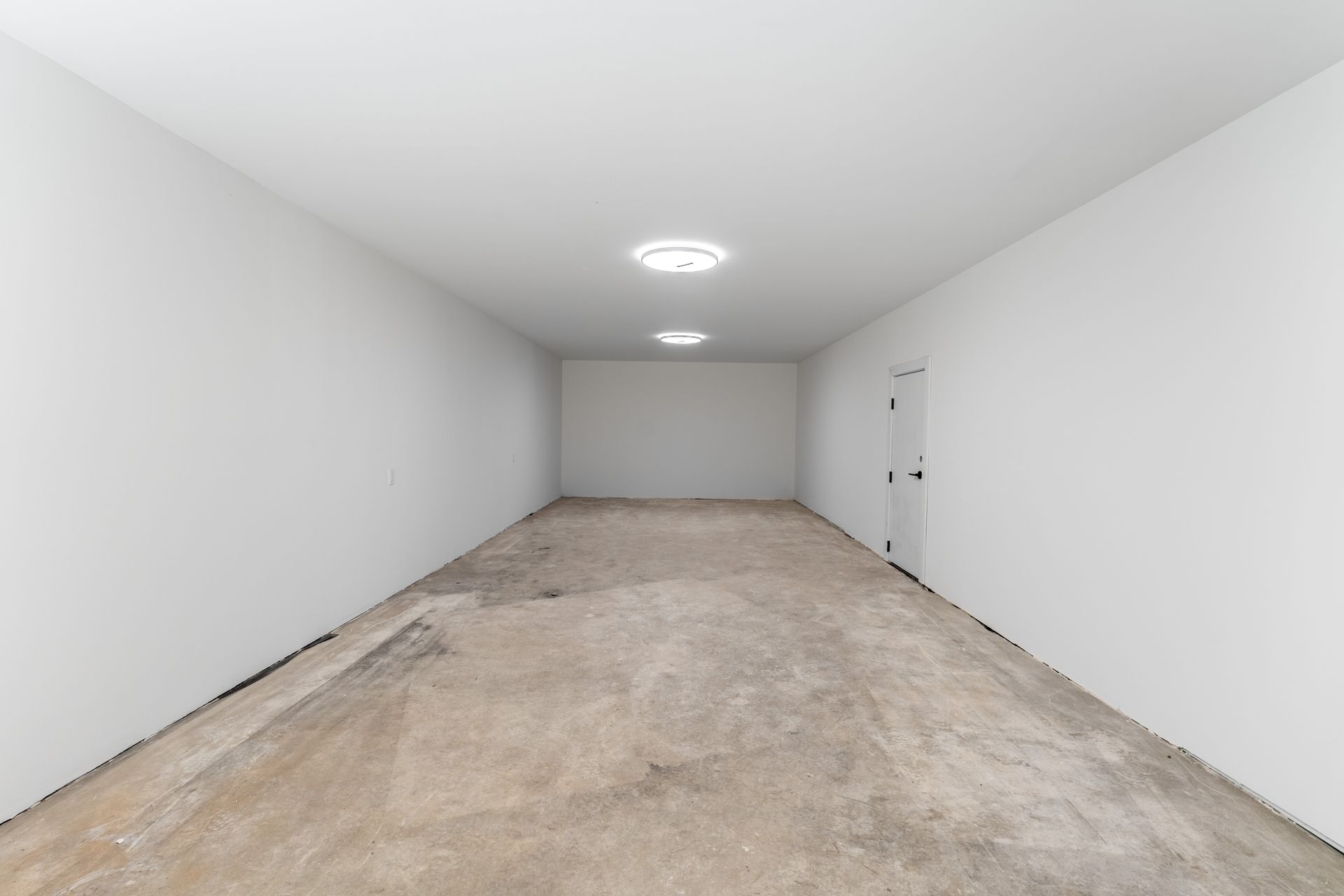 An empty room with white walls and a concrete floor