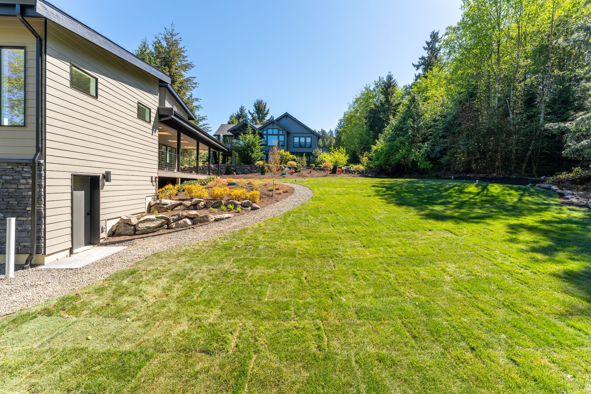 A large lawn in front of a house with trees in the background.