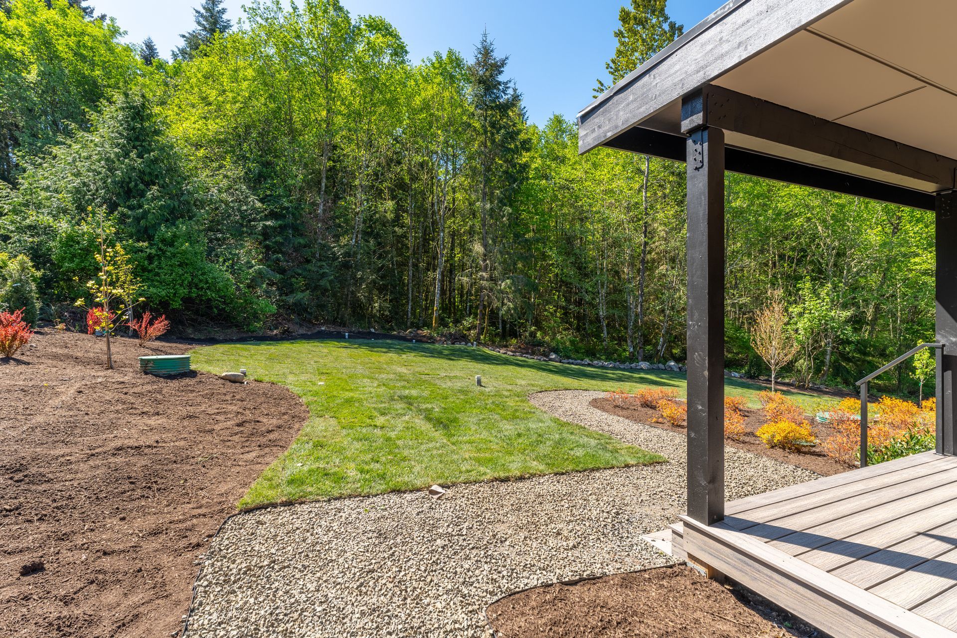 A backyard with a lush green lawn and trees in the background.