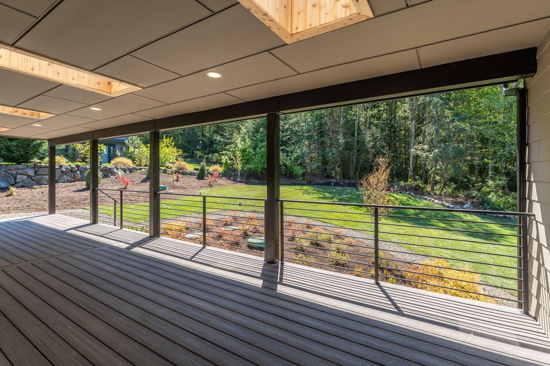 A large covered deck with a view of a lush green field.