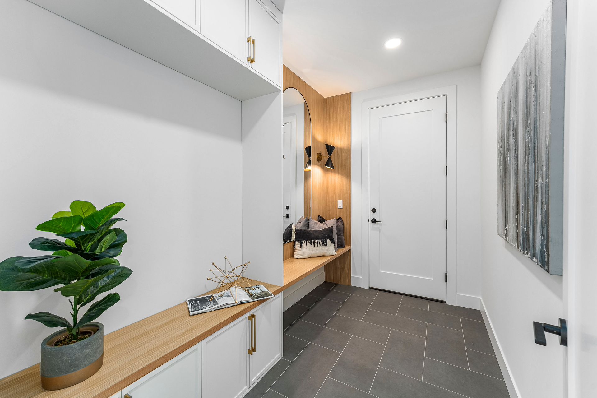 A hallway with a plant on a shelf and a painting on the wall.