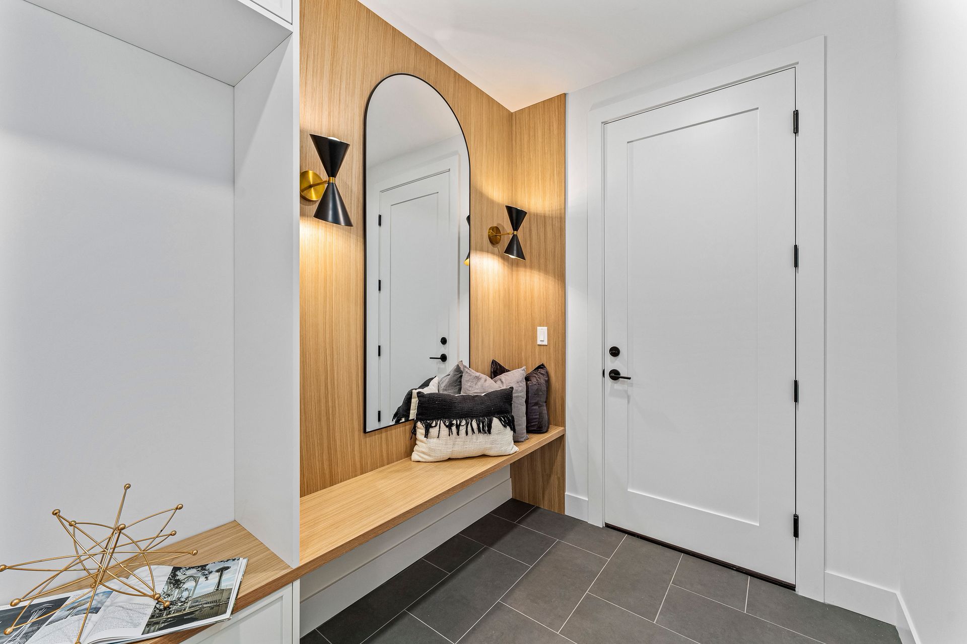 A hallway with a large mirror on the wall and a bench.