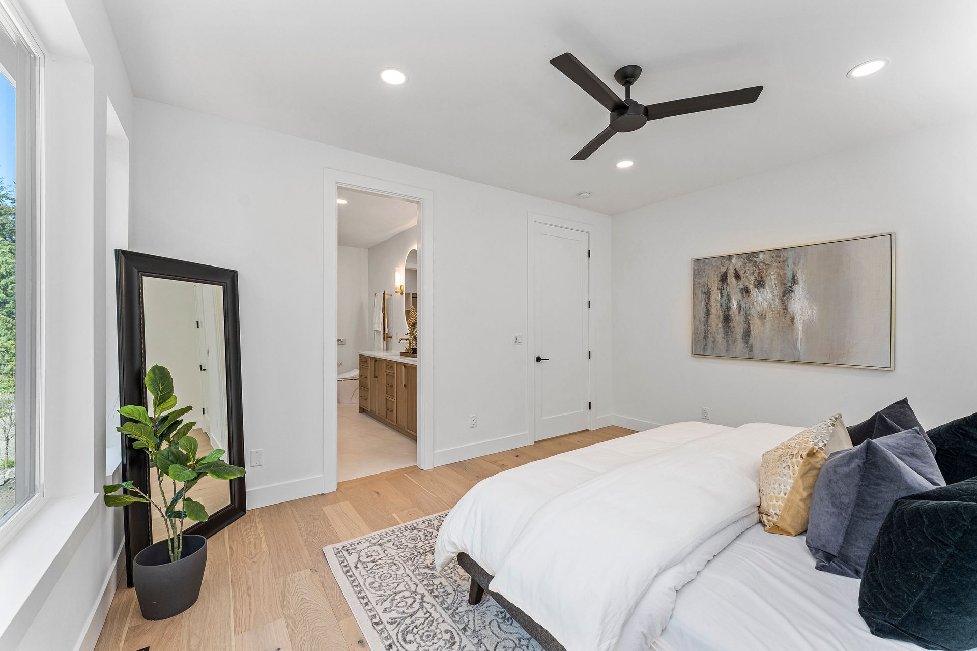 A bedroom with a bed , mirror and ceiling fan.