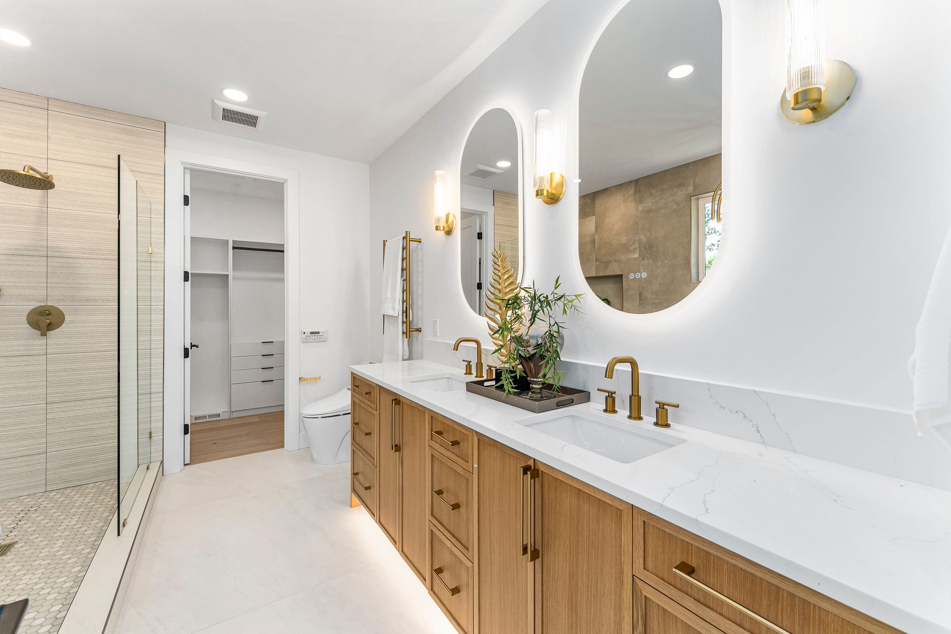 A bathroom with two sinks , two mirrors , a toilet , and a walk in shower.