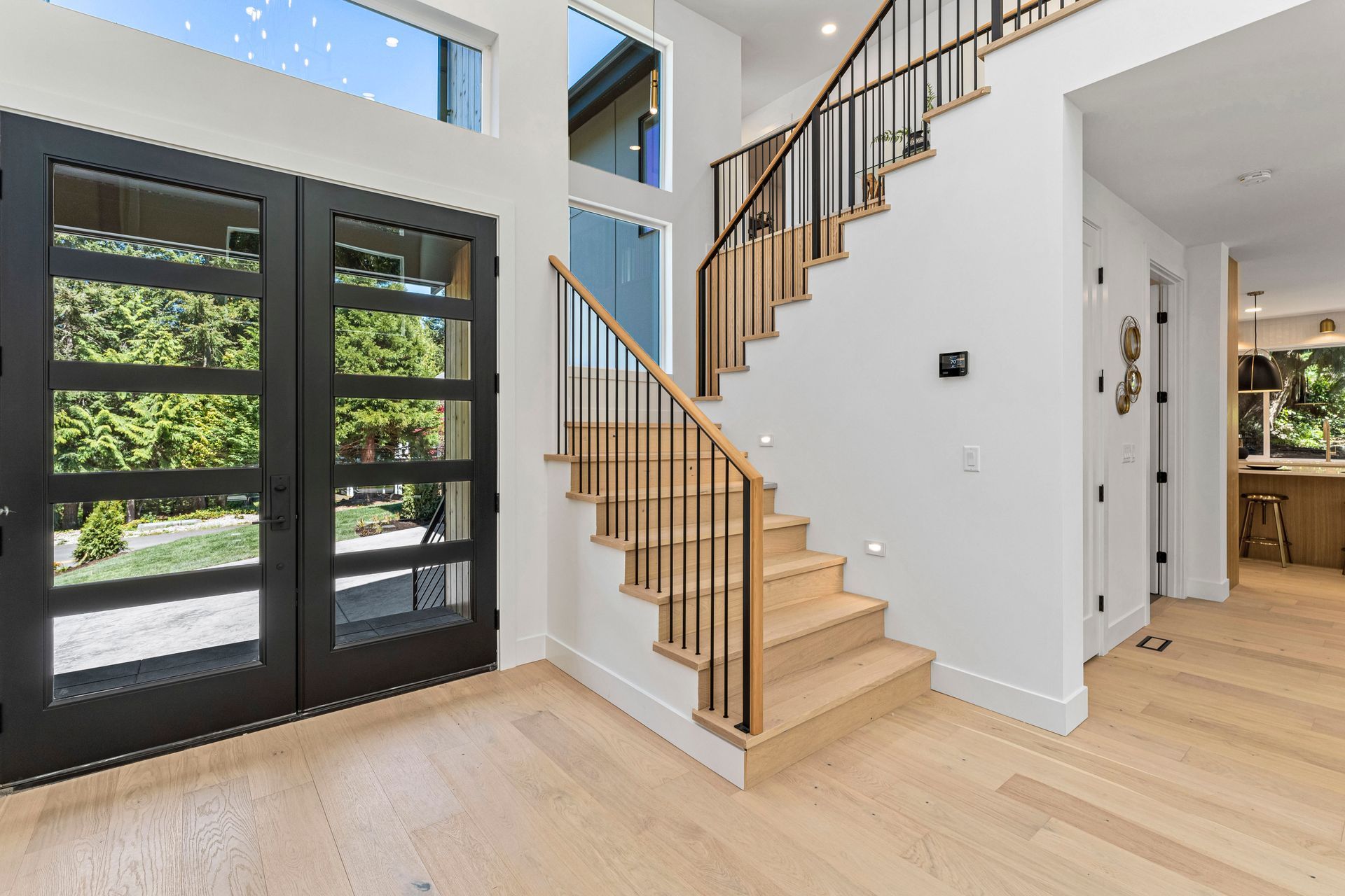 A staircase in a house with a wooden railing and a black door.