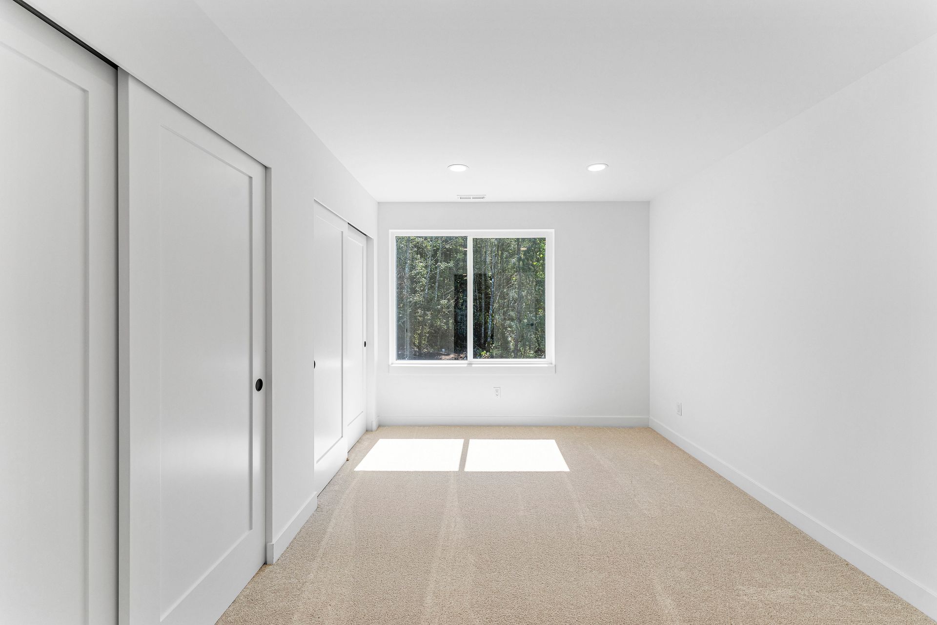An empty room with a window and a carpeted floor.