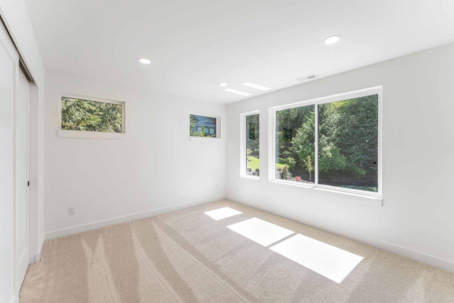 An empty room with a lot of windows and carpet.