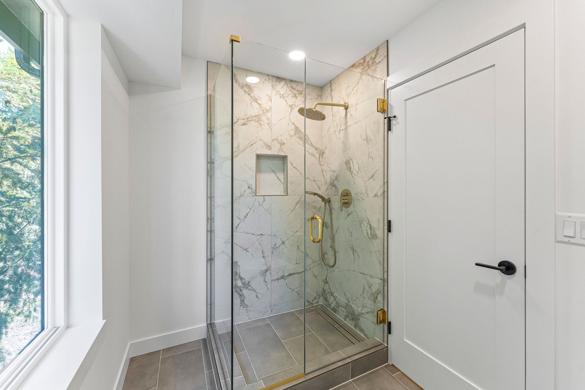 A bathroom with a walk in shower and a window.