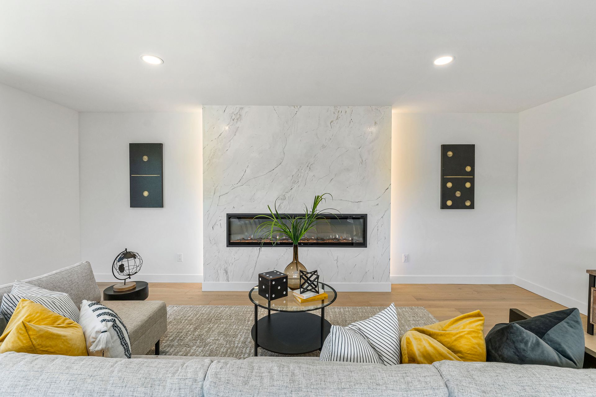 A living room with a couch , fireplace , coffee table and dominoes on the wall.