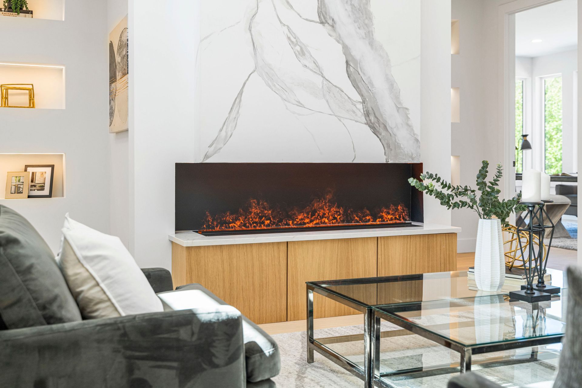 A living room with a fireplace , couch , coffee table and marble wall.